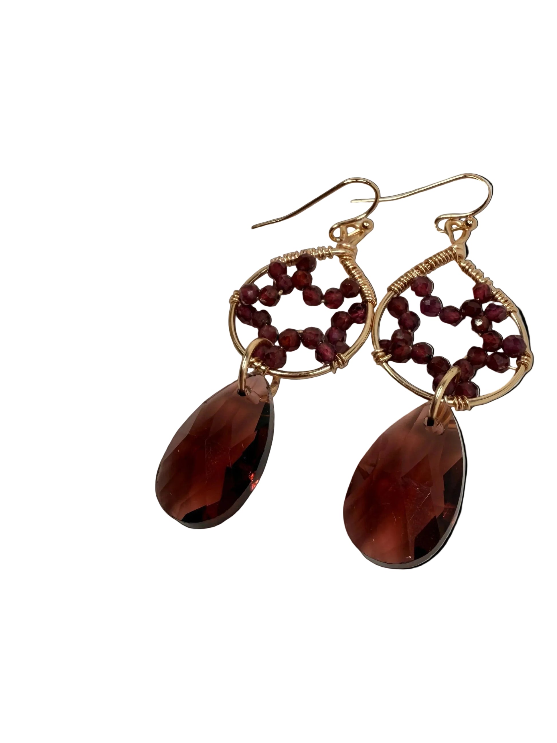 Pair of earrings with red beads and brown teardrop shapes on a light background