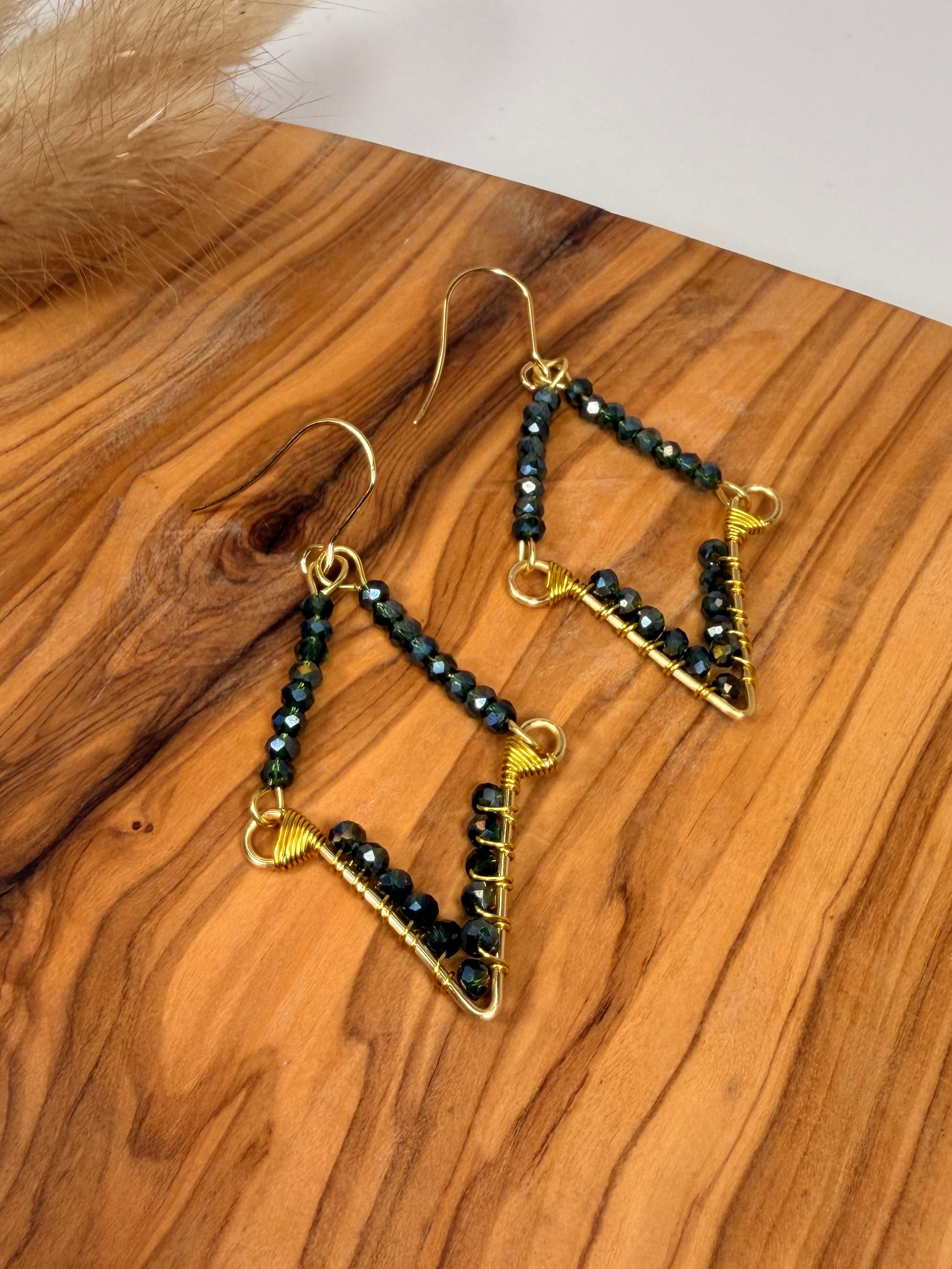 Gold and black beaded earrings on a wooden surface