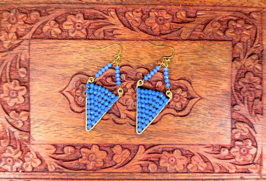 Blue triangle-shaped earrings on a wooden box with floral patterns